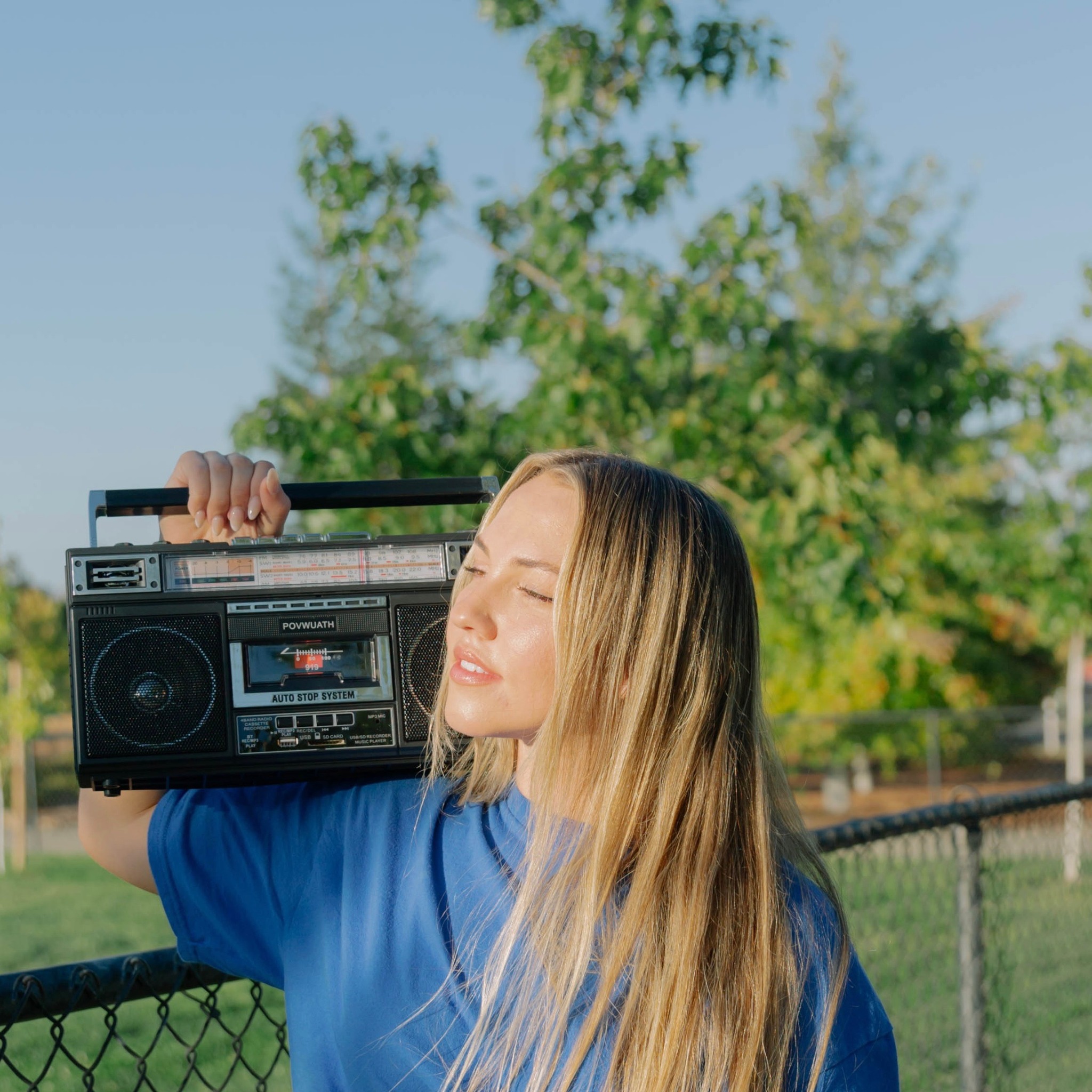 Madelynne West outdoors holding a vintage boombox